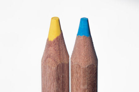 two colored pencils, blue and yellow, symbolize the colors of the flag of Ukraine, on a white backgroundの写真素材