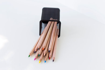 multi-colored pencils fell out of a fallen stationery glass on a white backgroundの写真素材