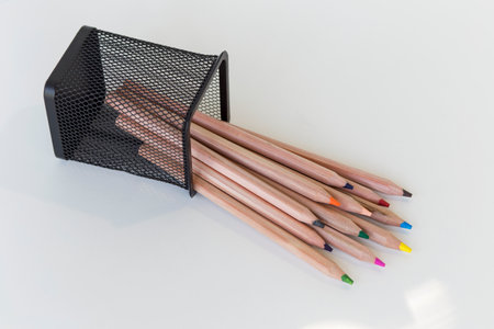 multi-colored pencils fell out of a fallen stationery glass on a white backgroundの写真素材