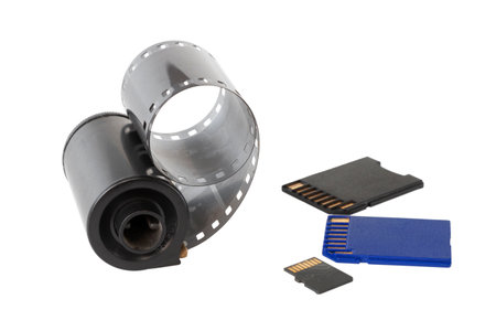 Micro SD card against vintage roll film in reel, on isolated backgroundの写真素材