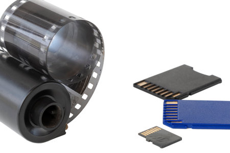 Micro SD card against vintage roll film in reel, on isolated backgroundの写真素材