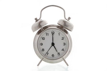 small metal alarm clock on a white background, time is 5 o'clockの写真素材
