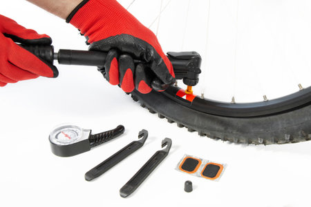 inflate a flat tire of a bicycle with a hand pump, close-up, on an isolated white backgroundの写真素材