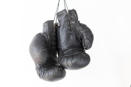 hanging old worn leather boxing gloves isolated on white backgroundの写真素材