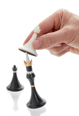 The hand holding the chess piece, the pawn beats the king, Checkmate, Business concept strategy, leadership, victory of white over black, on isolated white backgroundの写真素材