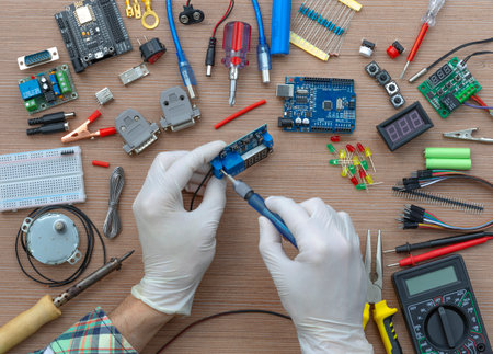 An engineer's hands are assembling a breadboard from an Arduino microcontroller, surrounded by electronics tuning tools. View of the electronic laboratory bench with peripherals and expansion boards.の写真素材