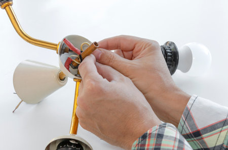 master repairs a disassembled electric lamp, close-up repair of a chandelier on a white background