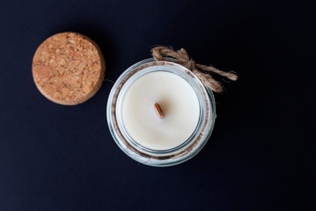 aromatic candle with a wooden wick in a glass candlestick, close-up on a dark background