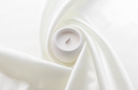 aromatic candle with wooden wick in plaster candlestick, twisted white fabric in the background, handmade conceptの写真素材