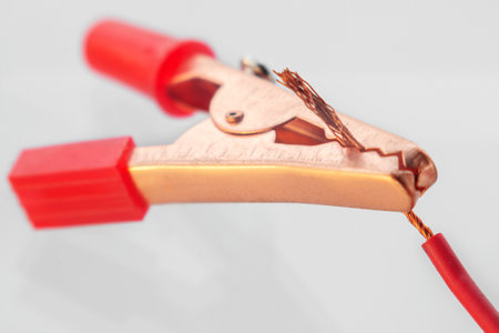 Red clamp attached to bare wire, macro, isolated on whiteの写真素材