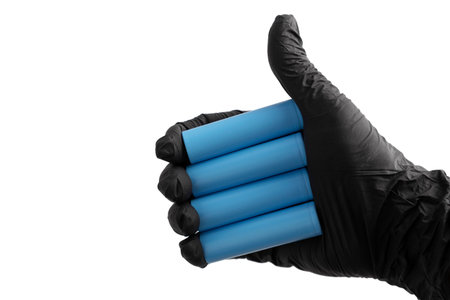 Hand in black rubber glove with thumb up holding lithium-ion batteries type 18650, making ok sign. Concept of success. Close-up, cut outの写真素材