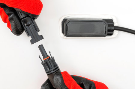 Close-up of technician's gloved hands connecting connectors of MC4 solar panels. Renewable energy concept.の写真素材