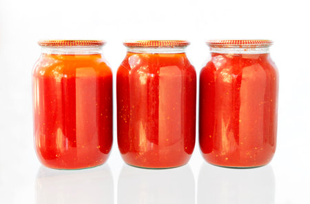 Jars of tomato juice. Canned tomato Juice prepared at home in glass, on isolated white background.の写真素材