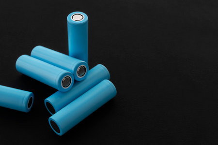 Stack of 18650 cylindrical batteries on black background, rechargeable lithium-ion batteries for electrical appliances and devices. Battery cell or secondary element. With copy space.の写真素材