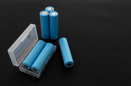 Stack of 18650 cylindrical batteries on black background, rechargeable lithium-ion batteries for electrical appliances and devices. Battery cell or secondary element. With copy space.の写真素材