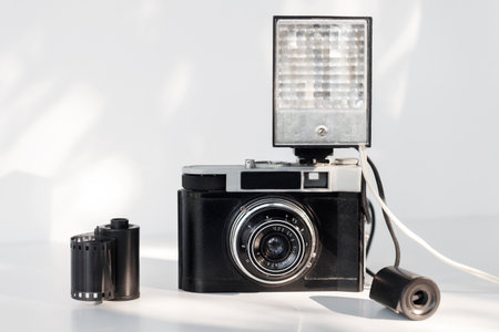 vintage camera with flash, film reel, on the white morning tableの写真素材