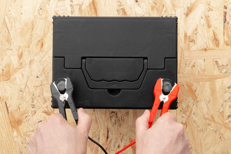 Top view of hands connecting positive and negative terminals of cables to car battery. AGM battery charging and testing concept.の写真素材