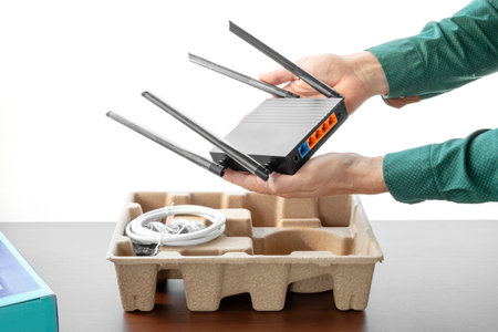 Man's hands holding new wifi router on isolated background. Unpacking new router.の写真素材