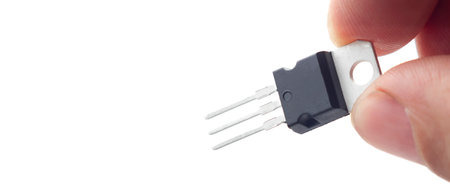 Hand holding a plastic transistor, voltage regulator encapsulated TO220, isolated on white backgroundの写真素材