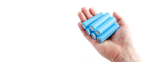 Hand holds light blue rechargeable lithium-ion battery type 18650 for electrical appliances and devices, on isolated background, with space for text.の写真素材