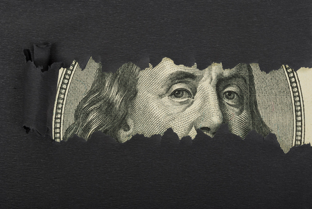 Benjamin Franklin macro peeking through torn black paperの写真素材