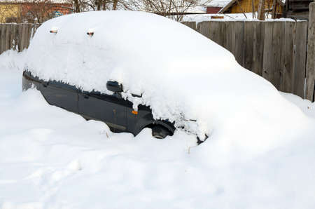 Car covered with snow in the winter snowfallの写真素材