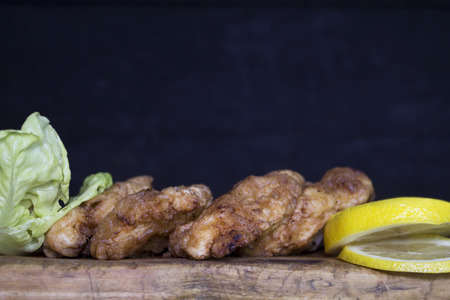 Breaded chicken meat with salad and lemon resting on a rustic wooden boardの写真素材