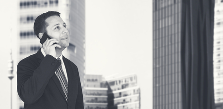 Businessman Talking On The Phone With Business City and Corporate Buildings In Backgroundの写真素材