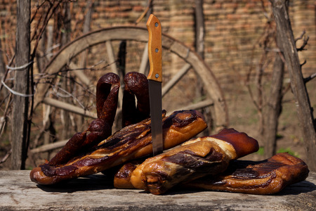Smoked Bacon and Dried Sausages With Butcher's Knife On A Rustic Wooden Surface. Delicious Domestic Foodの写真素材