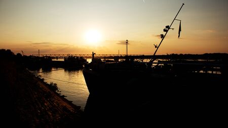 Beautiful Golden Sunset with Ships and Bridge Silhouettes At The River Danube in Belgrade Serbiaの写真素材