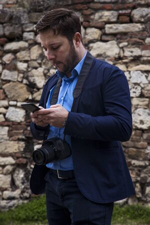 Photographer outdoors. Transfering photos from photocamera to smartphone and checking the images