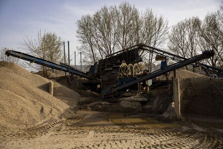 Machine sorting sand and gravel. Excavator and conveyer at the quarry