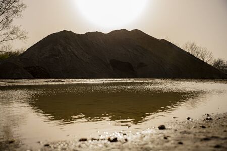 Sand and gravel excavation site with pile of gravel in the distance with sunset sky