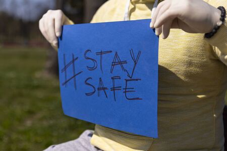 Stay safe sign on blue chroma key paper held by a man in surgical glovesの写真素材