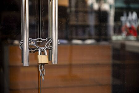 Closed Store due to Coronavirus pandemic. Locked Store Door with Padlock and Chains