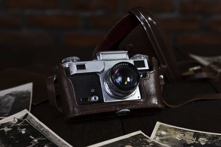 Vintage film camera and old photographs on a rustic surface 