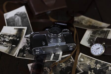 Vintage film camera and old photographs on a rustic surfaceの写真素材
