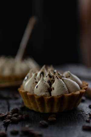 Cappuccino tart with cinnamon sticks and coffee beans on rustic wooden table 