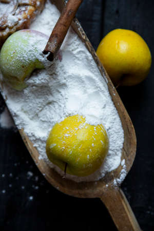 Apples in flour with cinnamon on an old textured wooden table. Apple pie recipeの写真素材
