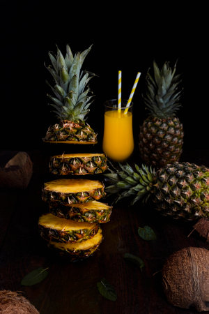 Pineapple flying in air cut in slices with juice in glass and Pineapples in background