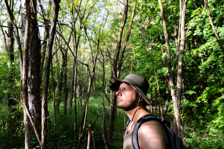 Hiker in the forest wearing military hat and backpack
