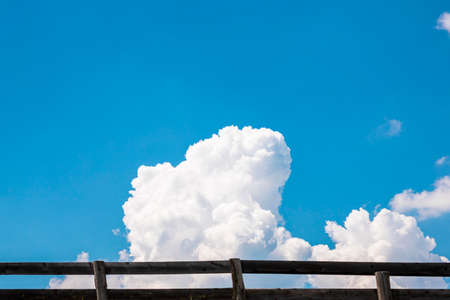 Blue sky and white fluffy clouds behind the wooden fence