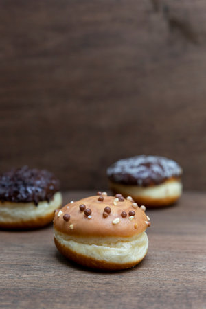 Delicious glazed chocolate donuts on wooden background