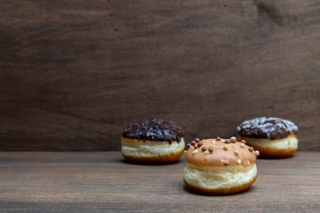 Delicious glazed chocolate donuts on wooden backgroundの写真素材