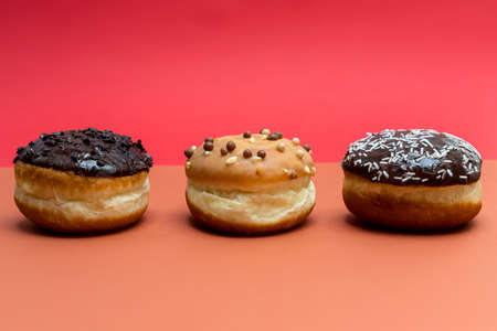 Delicious glazed chocolate donuts on vibrant background