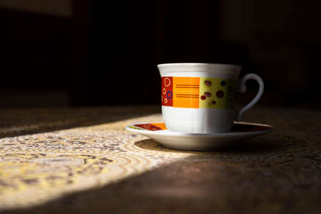 Coffe cup on the kitchen table shined by the sunの写真素材