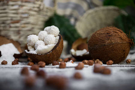 Coconut candy, balls, coconuts and hazelnuts on a rustic wooden surfaceの写真素材