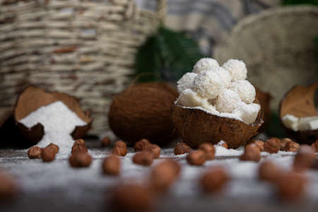 Coconut candy, balls, coconuts and hazelnuts on a rustic wooden surfaceの写真素材