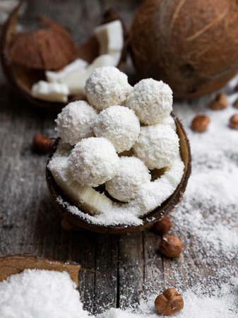 Coconut candy, balls, coconuts and hazelnuts on a rustic wooden surfaceの写真素材