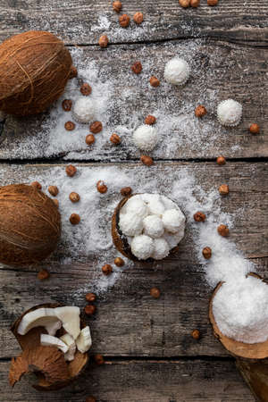 Coconut candy, balls, coconuts and hazelnuts on a rustic wooden surface. Top viewの写真素材